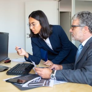 lider negocios masculino enfocado asistente femenina mirando informe estadistico monitor pc sosteniendo graficos comerciales papel vista lateral concepto expertos financieros 74855 14240